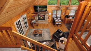 Een houten chalet met een open haard, eethoek en uitzicht op het bos.