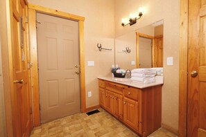 A bathroom with wooden cabinets, a sink with towels, a mirror, and a door. - Log cabin with pool table & hot tub-sleeps 8! (Pigeon Forge)