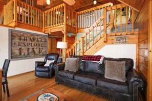 L’intérieur d’une cabine, avec un canapé en cuir, un fauteuil, un escalier et un plafond en bois.