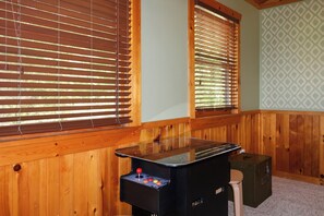 Une pièce aux murs recouverts de panneaux de bois, une table avec un plateau en verre et un joystick, et un mur orné d’un motif vert.