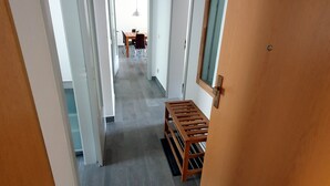 Un couloir avec un banc en bois, une porte et une vue sur une salle à manger.