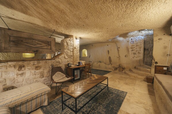 Un intérieur rustique en pierre, avec un banc en bois, une petite table et une chaise.