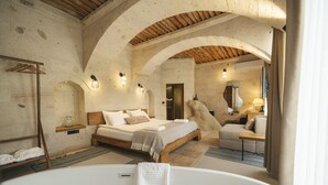 Ein Schlafzimmer mit einem großen Bett, einer Holzbalkendecke und einer Badewanne.