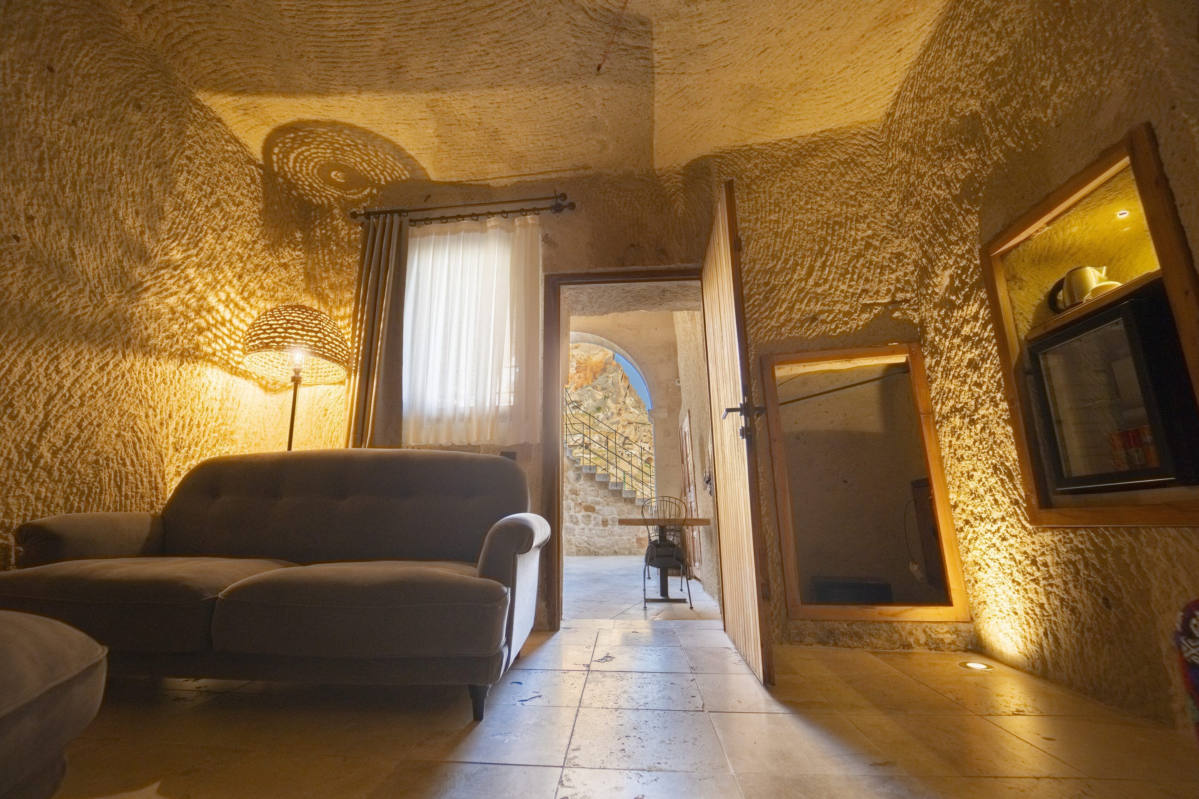 A cozy room with a sofa, a lamp, and a stone wall.