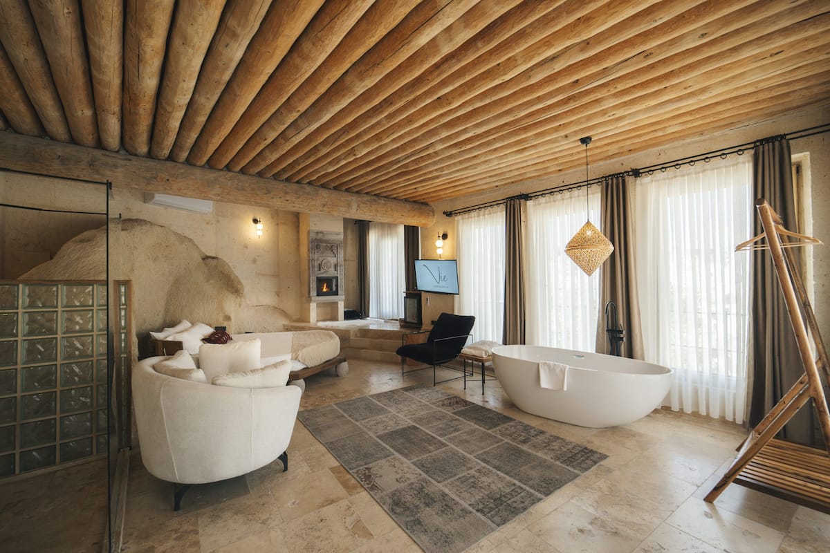 Una habitación amplia con una bañera grande, un sofá blanco y un techo de madera.