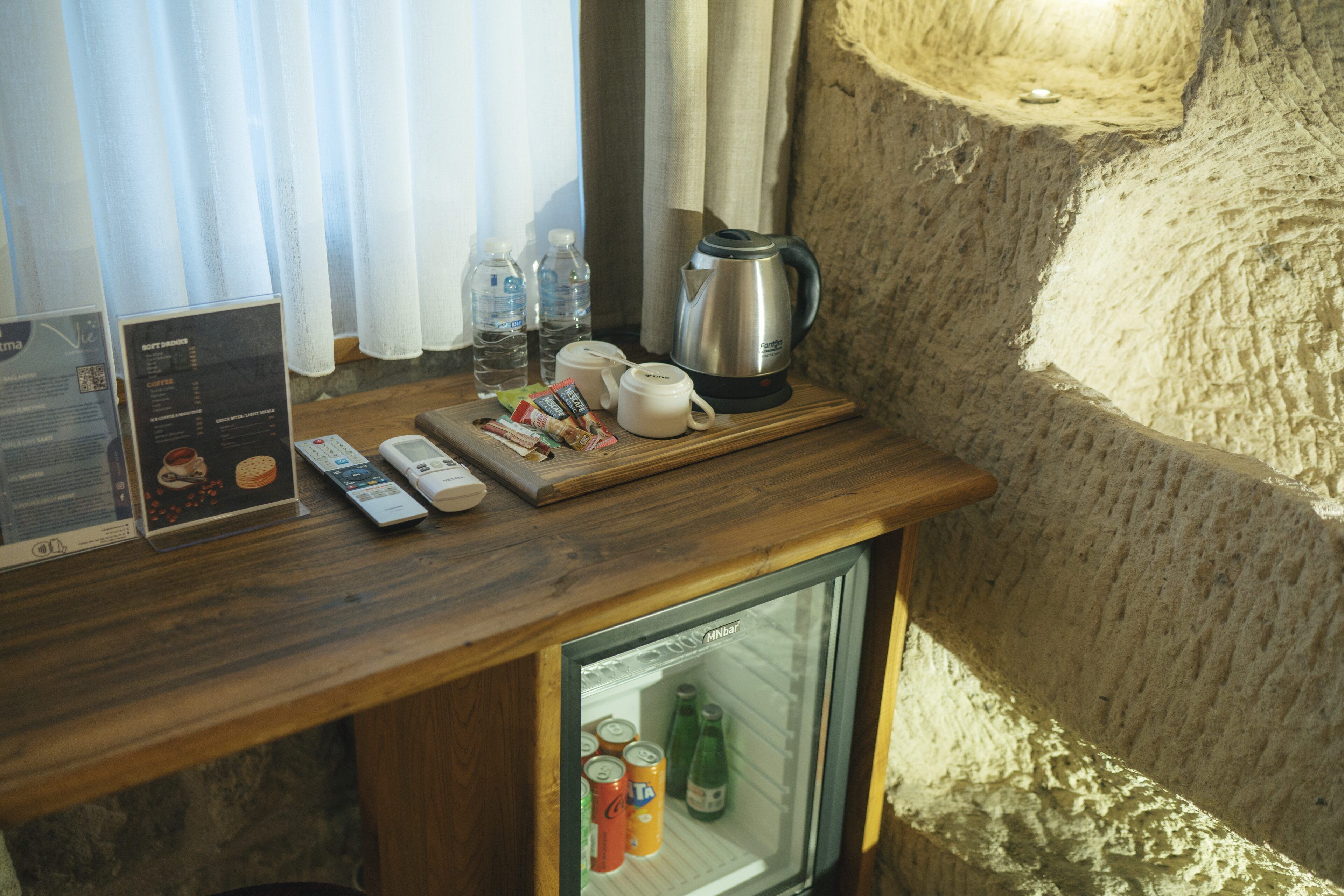 A minibar with a wooden counter, a coffee maker, bottled water, and snacks.