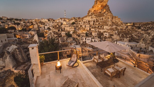 Eine Dachterrasse mit Blick auf eine historische Stadt, eine Felsformation und eine Moschee.