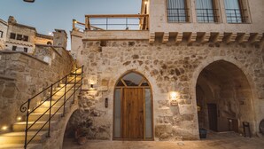 Ein Steinhaus mit einer Holztür, einer Treppe und einem Balkon.