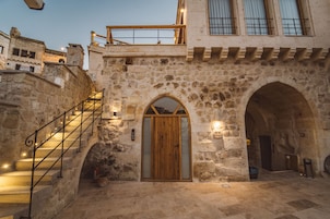 Un edificio de piedra con puerta de madera, una escalera y un balcón.
