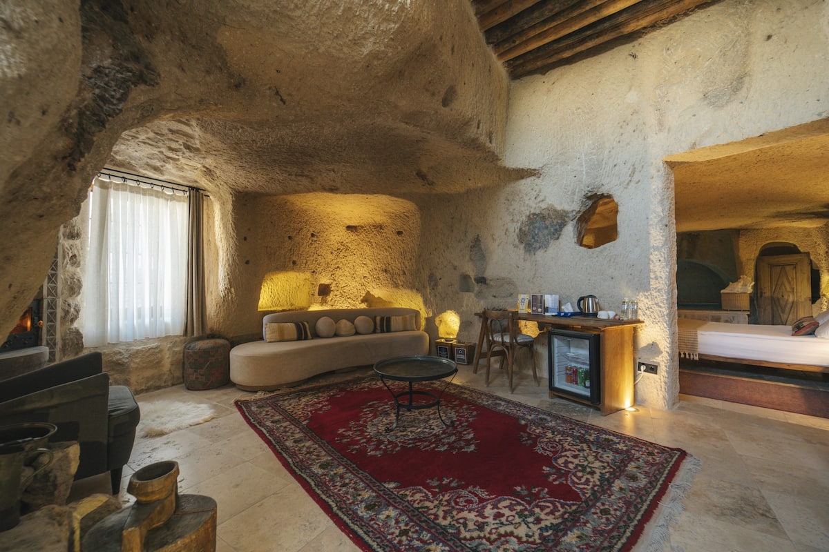 Un interior acogedor y rústico con una pared de piedra, un sofá, una zona de comedor y una cama.