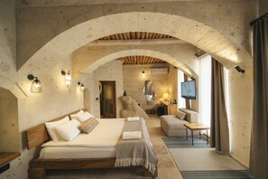 Un dormitorio amplio con una cama grande, cabecera de madera y un arco de piedra.