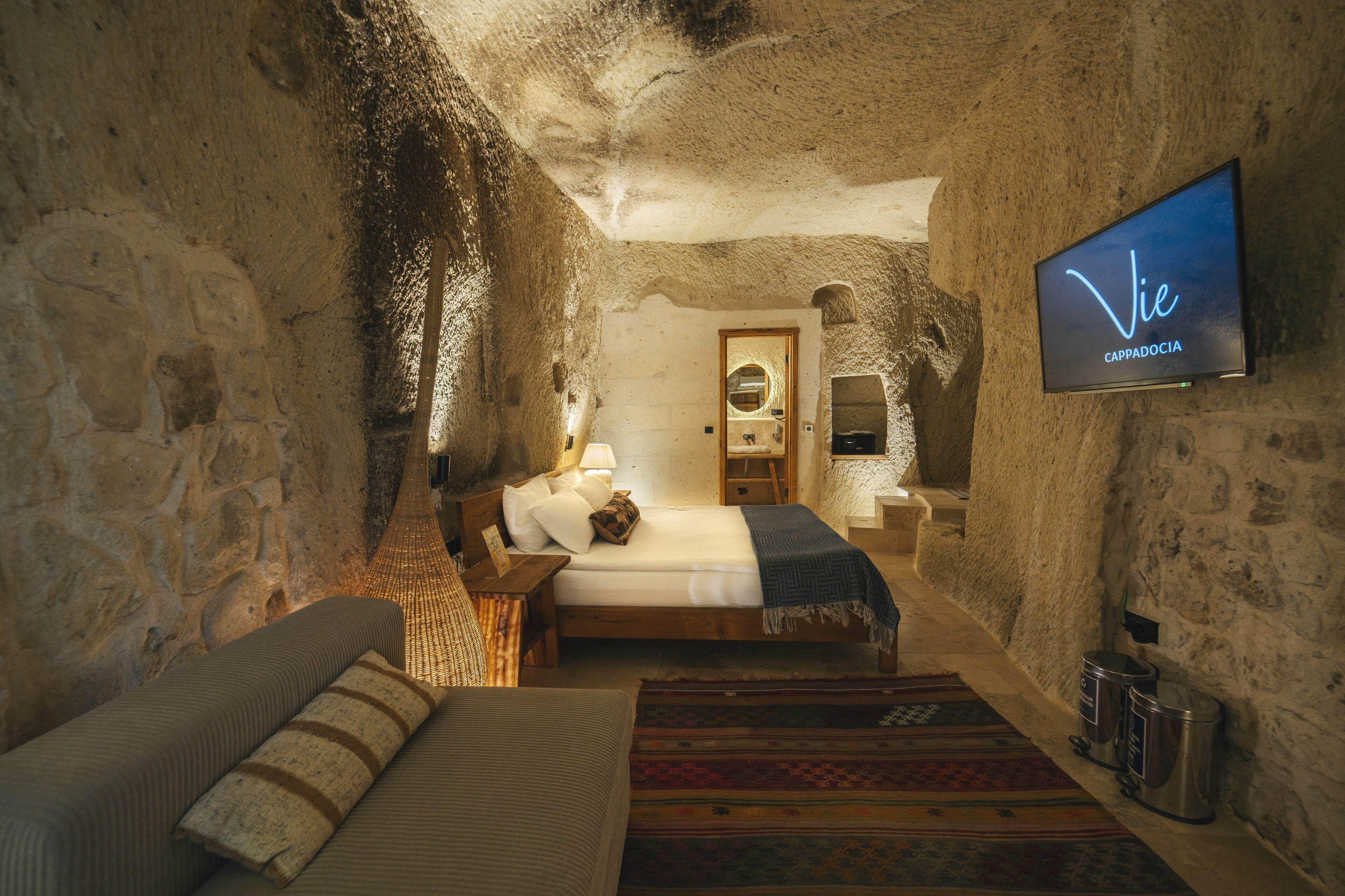Une pièce confortable avec un lit, un canapé, un téléviseur fixé au mur et une petite table avec une lampe.