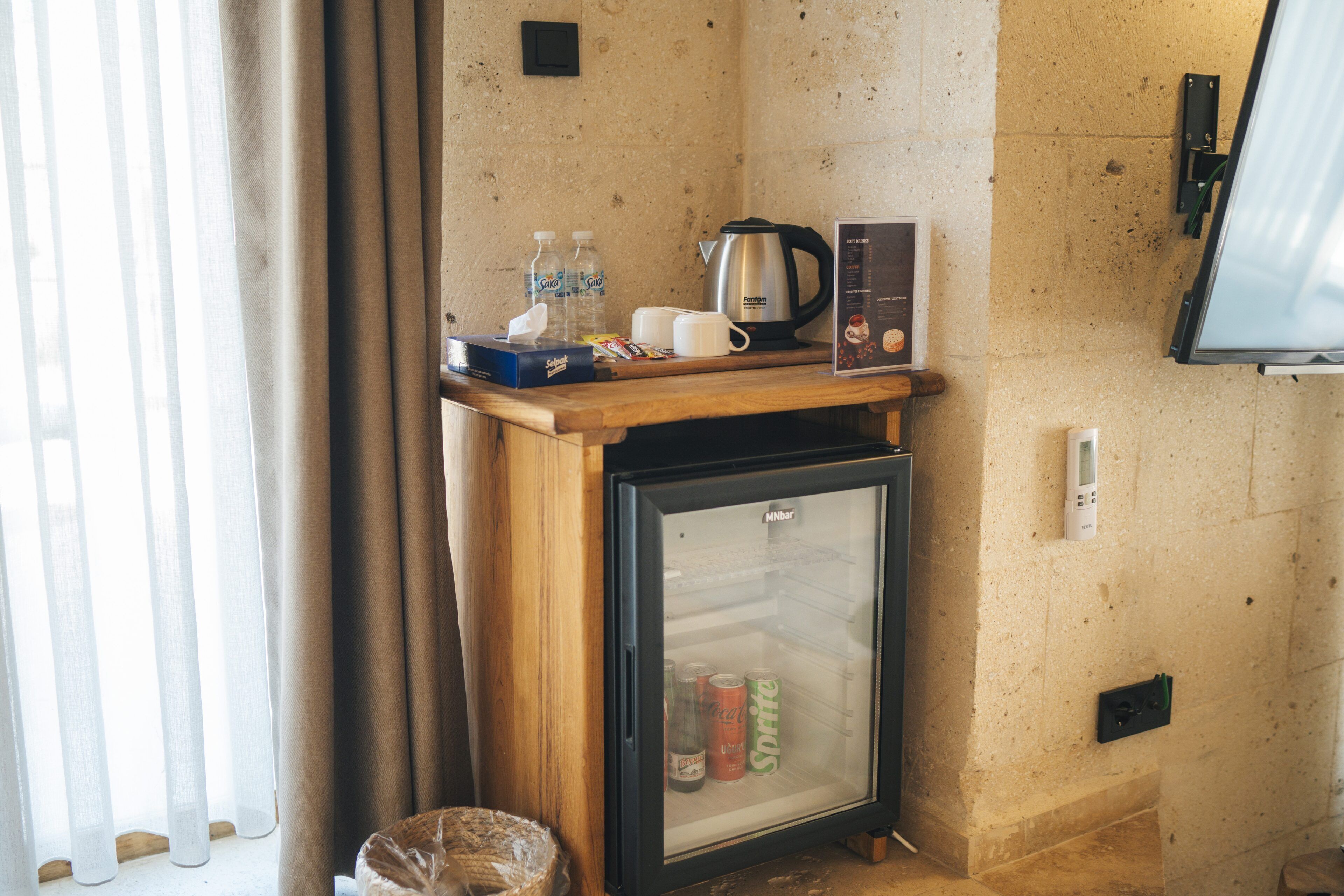 Un mini-bar compact comprenant un réfrigérateur, une machine à café et des bouteilles d’eau.