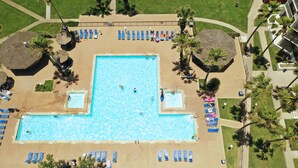 Vista aérea de una piscina con múltiples carriles, rodeada de tumbonas y palmeras.
