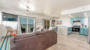 Una sala de estar moderna con sofá, comedor, cocina y un balcón con una silla.