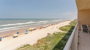 Vista de la playa con sombrillas, sillas y un cielo despejado.