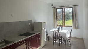 A compact kitchen with a sink, stove, and dining table with chairs.