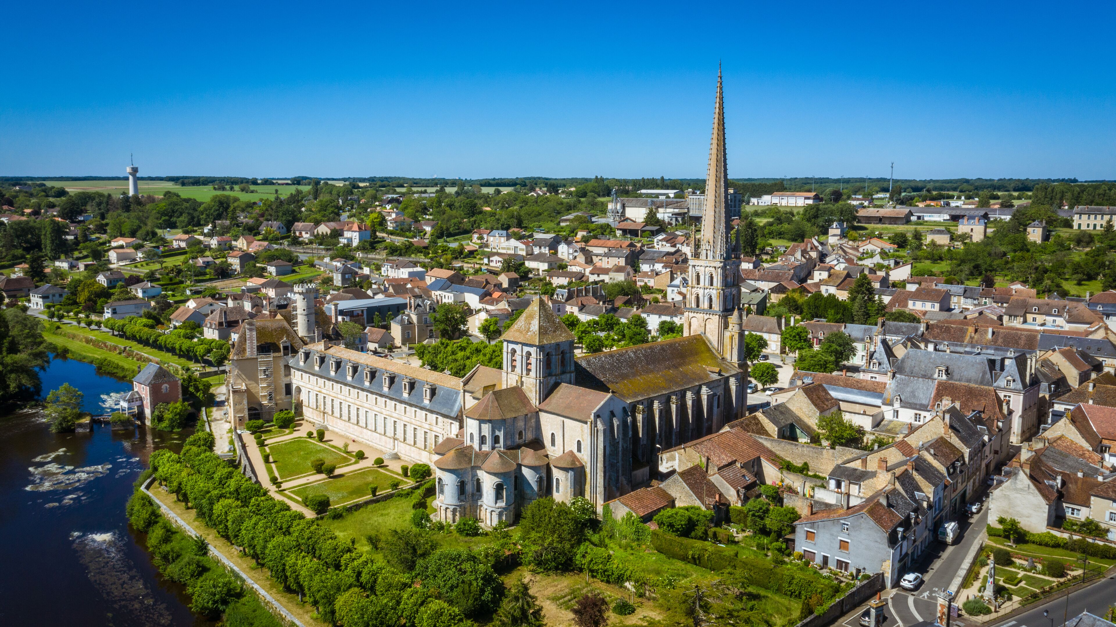A historic town with a prominent church featuring a tall spire, surrounded by residential buildings and a river.