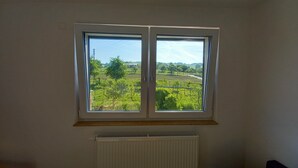 Ein Zimmer mit einem Doppelblickfenster mit Blick auf eine grüne Landschaft.