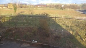 Ländliche Landschaft mit einem eingezäunten Feld, einem Gebäude mit rotem Dach und einer Straße.