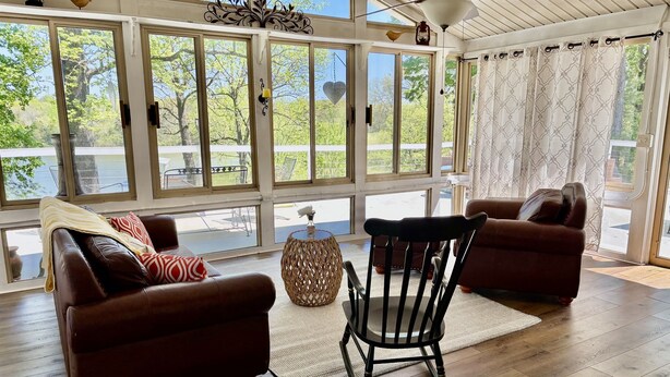 A sunlit room with large windows, a ceiling fan, and a view of a deck. - Grand Lake Estate Luxury Waterfront Retreat (Mount Juliet)