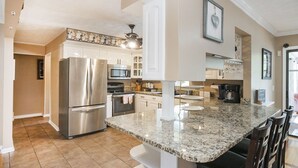 A modern kitchen with stainless steel appliances, a granite countertop, and white cabinetry. - Grand Lake Estate Luxury Waterfront Retreat (Mount Juliet)