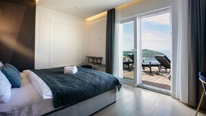 Moderni hotellihuone, jossa on suuri sänky, työpöytä ja parveke, jolta on näkymä.
