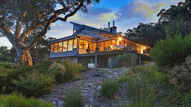 A modern house with large windows, a stone facade, and a spacious outdoor area with a fire pit. - Sydney View - 70km from Sydney; 1000km from care! (Woodford)