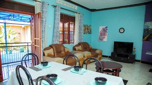 A dining area with a table set for four, a sofa, and a television in a room with blue walls.