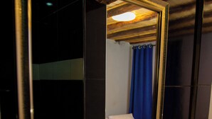 A bathroom with a large mirror, a sink, and a bed with a blue curtain.