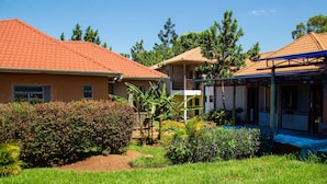 A residential area with houses featuring red-tiled roofs, surrounded by lush greenery and a well-maintained lawn.