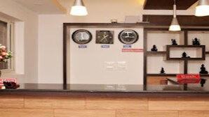 Un mostrador de recepción con relojes, un florero y un cartel que dice 'Cashier'.