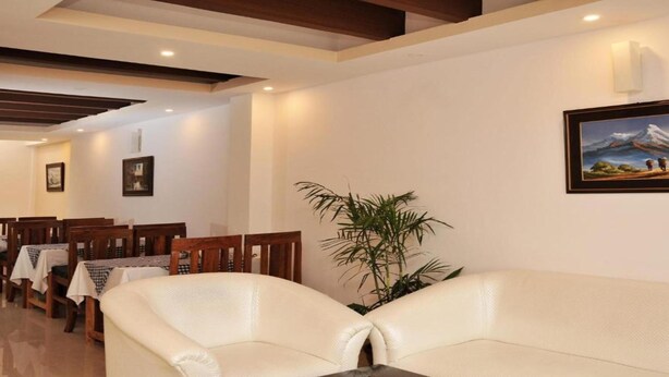 Un vestíbulo de hotel con zona de comedor, un sofá y un cuadro en la pared.