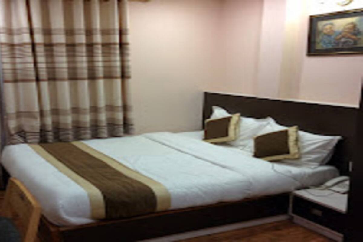 Una habitación de hotel con cama, mesita de noche y un cuadro en la pared.