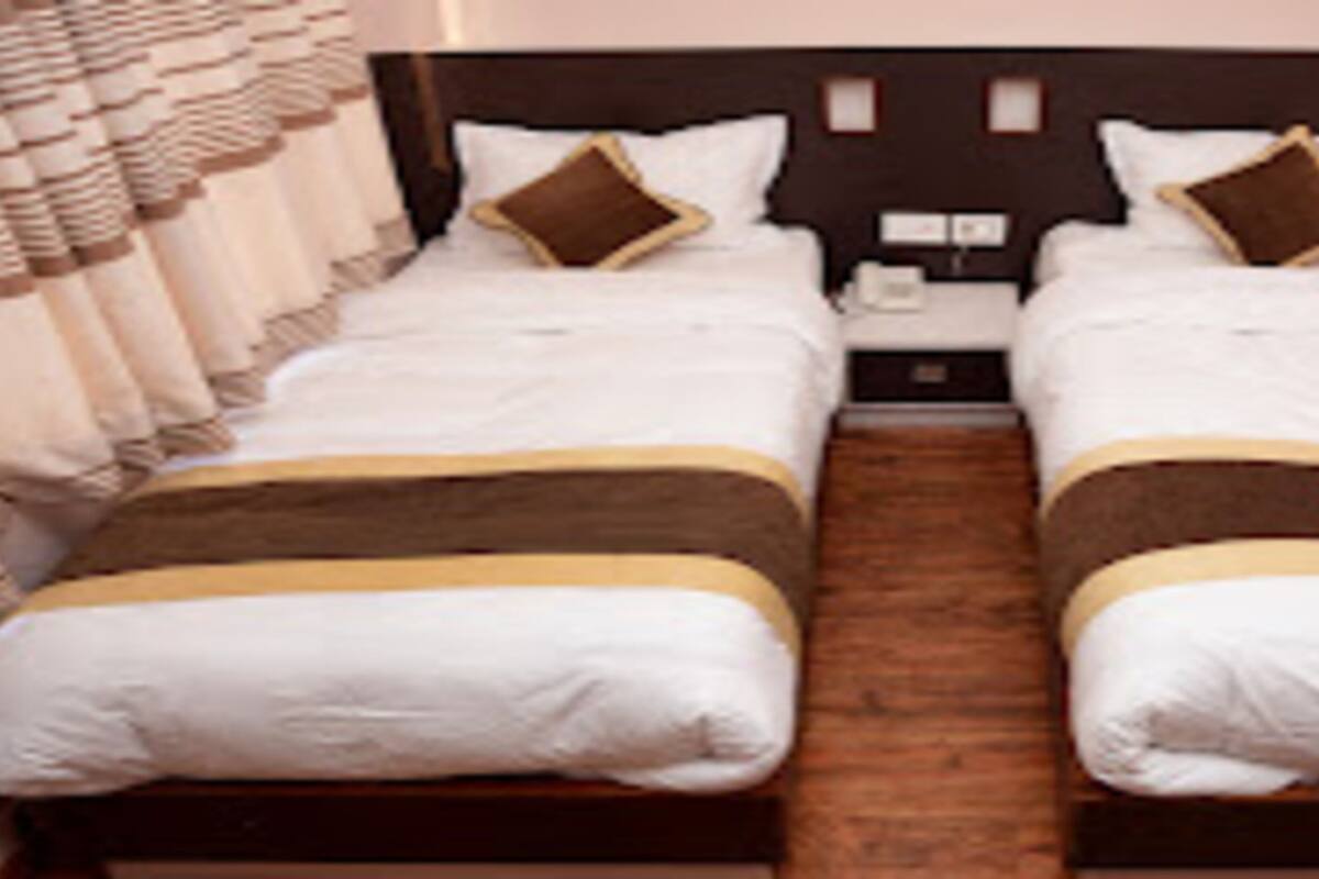 Una cama doble con cabecera de madera, dos almohadas y una mesita de noche con lámpara.