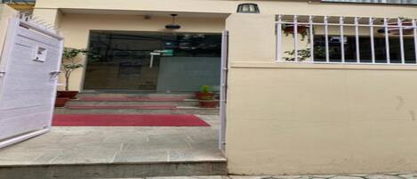 A building entrance with a gated door, a red carpet, and steps leading to a door.