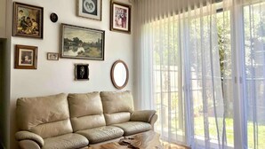 Un saló amb un sofà de cuir beix, una taula de centre i un finestral gran amb cortines transparents.