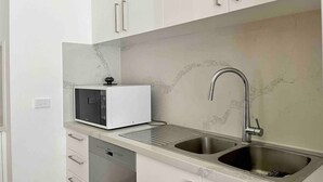 Cuina amb armaris blancs, microones integrat, rentaplats i un rentamans de thép inoxidable.