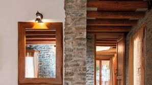 A stone pillar, wooden desk, and chair in a hallway with a wooden ceiling and stone walls.