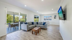 A modern living room with a sectional sofa, a wooden coffee table, and a TV mounted on the wall.