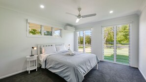 A modern bedroom with a bed, bedside tables, and a ceiling fan.