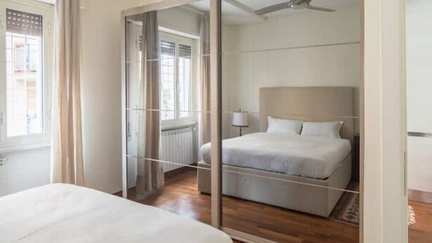 Una camera da letto con un letto, una ventola a soffitto e una finestra con tende.
