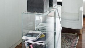Un interno moderno con un espositore in vetro che contiene libri e un'originale scultura arancione.