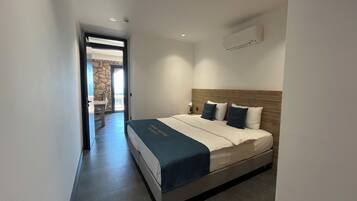 Una habitación de hotel con una cama, una mesita de noche, una lámpara y un aire acondicionado.