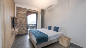 Un hotel moderno con una pared de acento de piedra, una cama con ropa de cama azul, una mesita de noche de madera y un televisor de pantalla plana montado en la pared.
