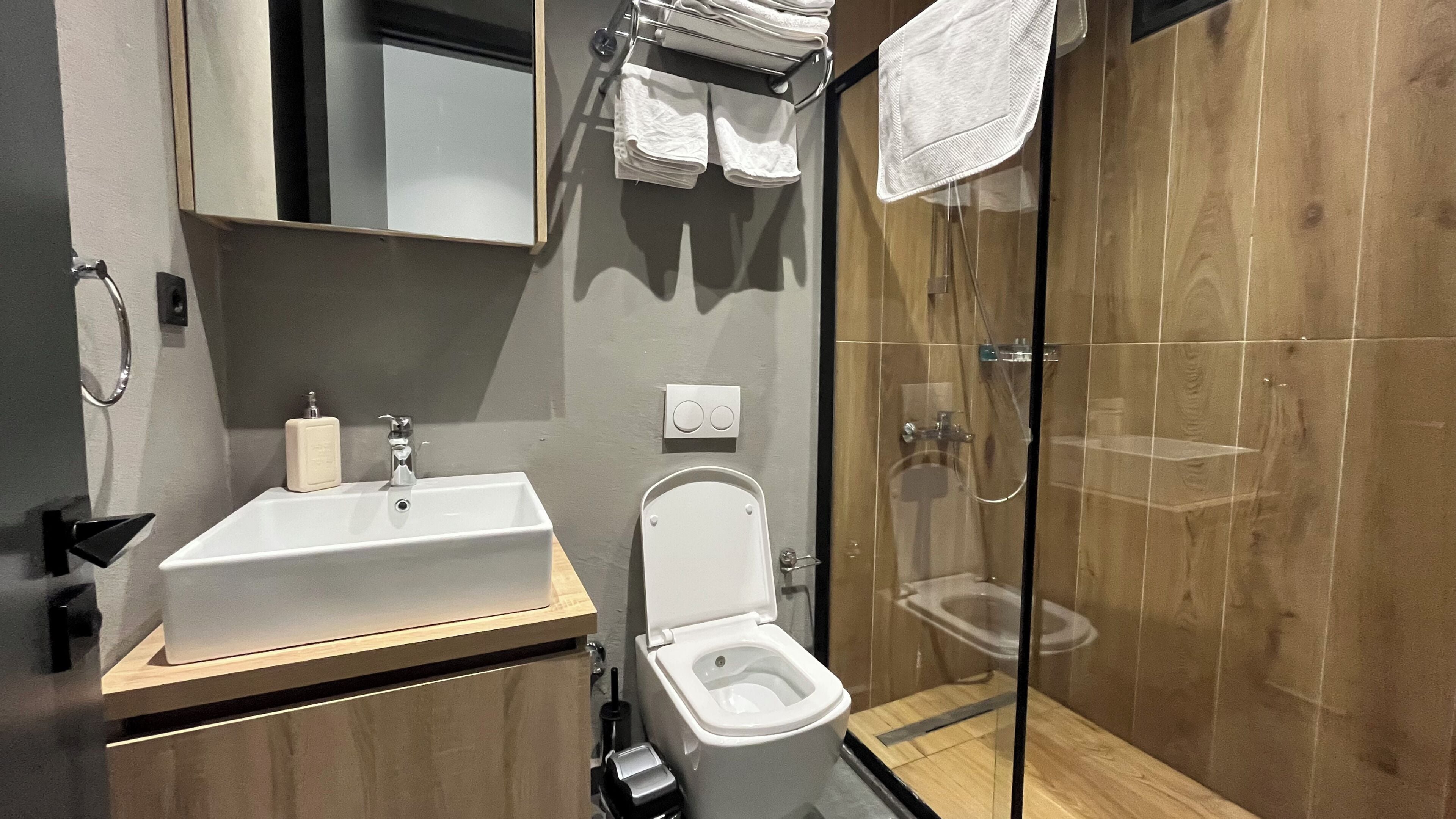 A modern bathroom with a sink, toilet, and glass-enclosed shower.
