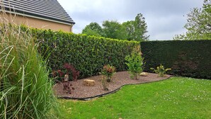 Ein gepflegter Garten mit vielfältigen Pflanzen und einer ordentlich geschnittenen Hecke.