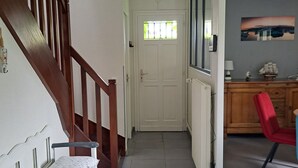 Ein Flur mit einer Treppe, einer Tür mit Fenster, einem roten Sessel und einem Schrank.