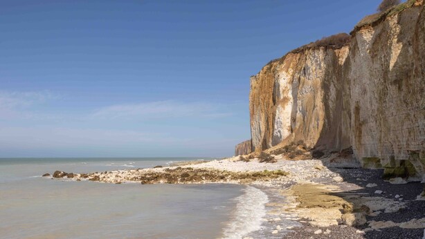 Eine Küstenlandschaft mit einer markanten Klippe und einem Strand.