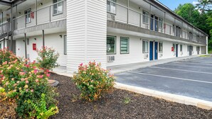 A multi-story motel with a parking lot and flower beds in front.